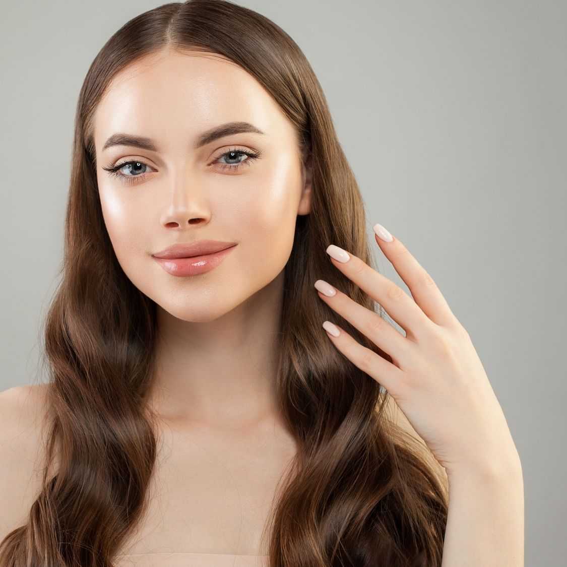 Woman posing with flawless complexion touching her face.