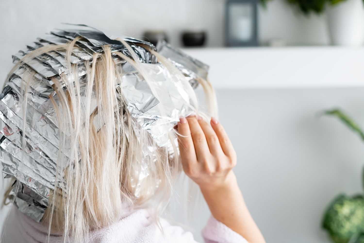 Person with foil in hair during a highlighting process at salon.