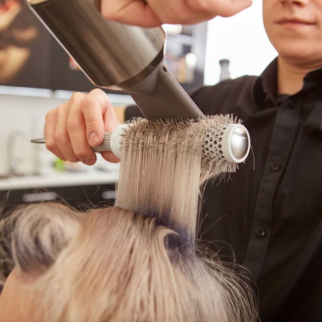 Hairdresser blow-drying and styling a client's hair.