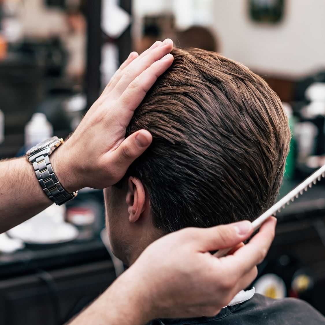 Barber combing a client's hair in a salon.